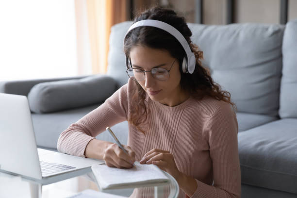 istock Woman listen audio course through headphones makes notes in copybook 1338521550