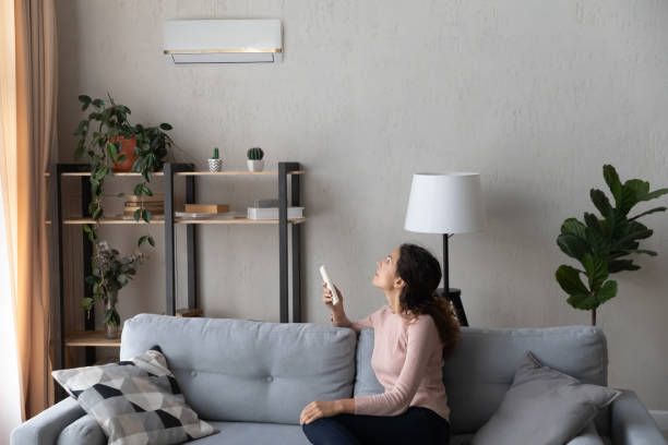 istock Woman sit on couch holding remote controller turns on airconditioner 1338521582