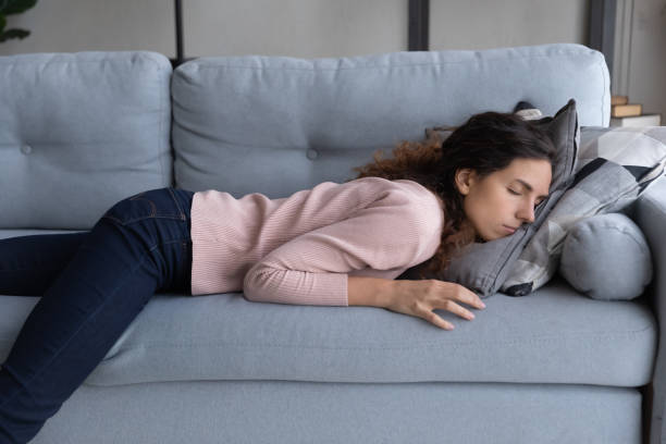 exhausted woman lying sleeping on sofa after sleepless night - cair no sofá imagens e fotografias de stock