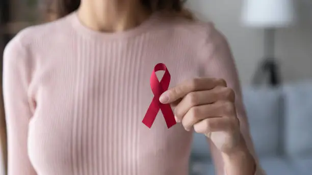 Photo of Close up female volunteer holding red ribbon in hands