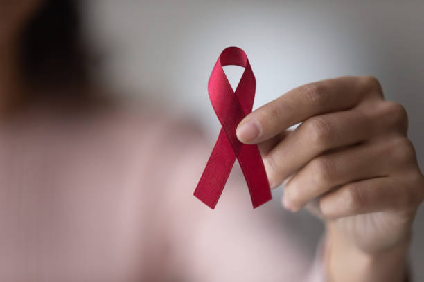 Close up focus on red ribbon in female hands Close up focus on red ribbon in female hands, woman standing indoor promote annual regular health check up, support people with chronic disease, social AIDS campaign, HIV awareness, healthcare concept hiv stock pictures, royalty-free photos & images