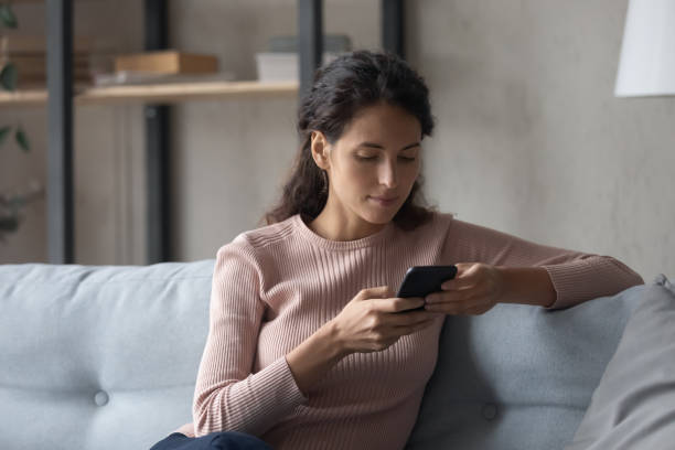 istock Serious woman sit on sofa hold cell phone use apps 1338521614