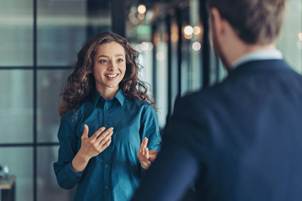 Businesswoman talking to a colleague Businesswoman and businessman talking in the office gesturing stock pictures, royalty-free photos & images