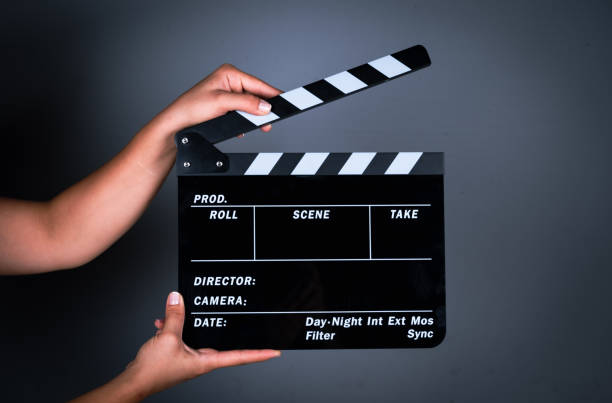 暗い灰色の背景に拍手板を持つ女性の手 - 映画撮影法 ストックフォトと画像