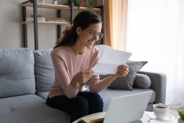 istock Lovely smiling woman sit on sofa reading letter 1338530310