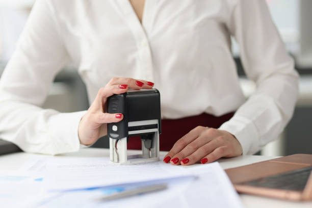 mujer de negocios pone sello en documentos de crédito en el escritorio del trabajo - notario fotografías e imágenes de stock