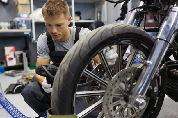 istock Man checks tire pressure on motorcycle in workshop 1338538842