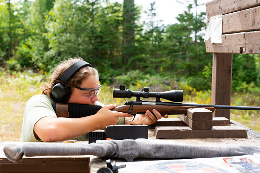 East asian teenage girl archer aiming at target in the playground under blue sky