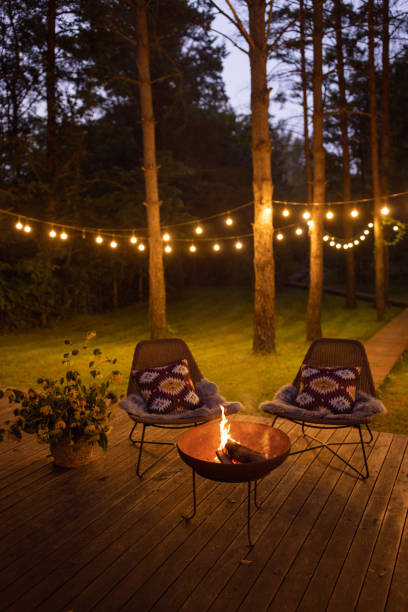Fire pit at cottage Comfortable arranged porch with fire pit and chairs. Autumn theme details. String lights in the background. cottage life stock pictures, royalty-free photos & images
