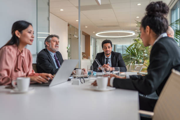 istock Multi-ethnic Group Of Businesspeople Conversing at Conference Table Before Meeting 1338554595