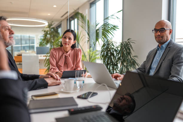istock Female Executive Presenting Ideas to Coworkers While Sitting in Board Room 1338554603