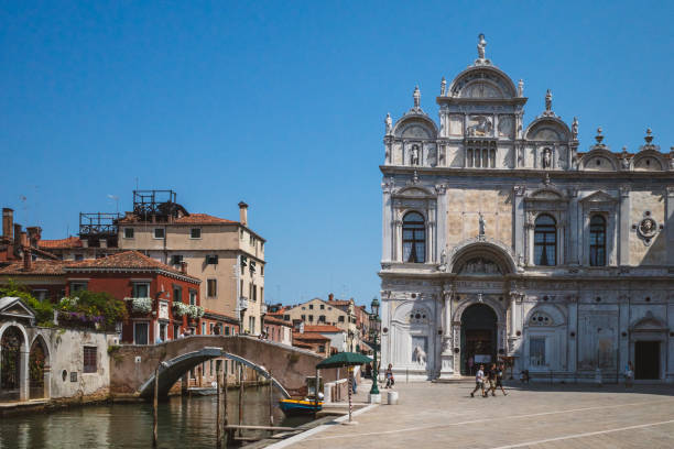 People walking past Scuola Grande di San Marco in Venice, Italy stock photo