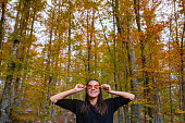 Smiling Woman Portrait covering her Eyes with Autumn Leaves