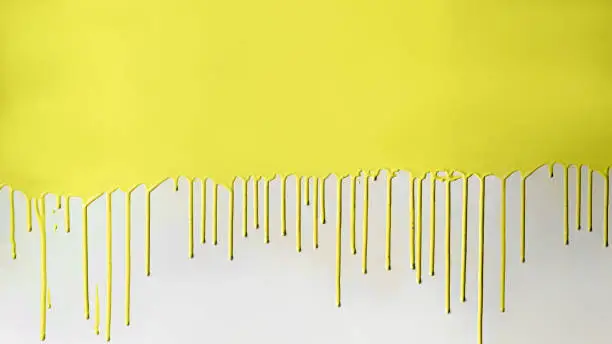 Yellow paint dripping on white wall