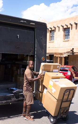 Taos, NM: A UPS driver unloading boxes on the historic Taos Plaza.
