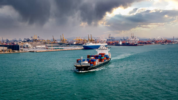 container ship transporting large cargo logistic import and export goods internationally worldwide and shipping port with storm cloud in the rain background and water front, industry business service transportation by container ship in sea high angle view buque portacontenedores que transporta gran carga logística importación exportación de mercancías internacionalmente en todo el mundo y envío portuario antecedentes industria servicio comercial transporte por buque portacontenedores en vista de alto �