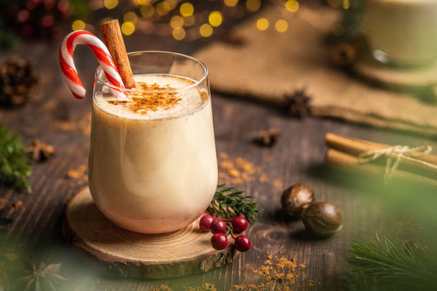 zabaione con cannella piccante. vacanze di natale e invernali, cocktail accogliente con cannella e canna da zucchero, bevanda natalizia tradizionale con noce moscata grattugiata e cannella, bevanda natalizia fatta in casa - hot drink alcohol green glass foto e immagini stock