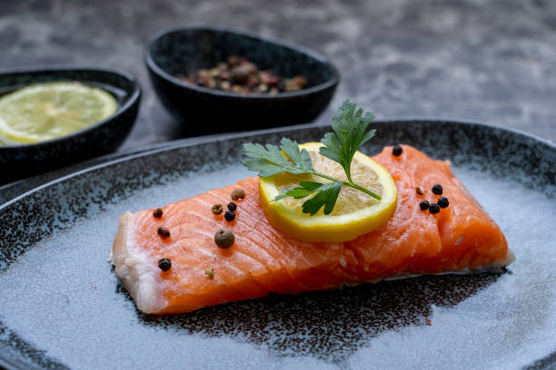 istock Row Salmon fish fillet uncooked with different spices and lemon slice served on plate. 1338597171