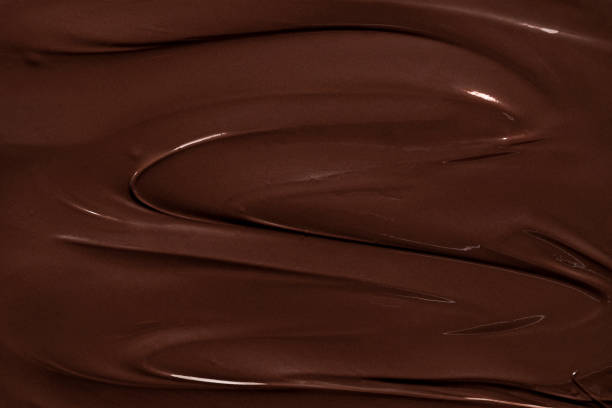 溶かしたチョコレートの質感、フルフレーム。ダークチョコレート渦巻きの背景