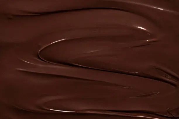 Melted chocolate swirl, macro image. Chocolate texture background. Liquid chocolate close-up. Baking ingredient.