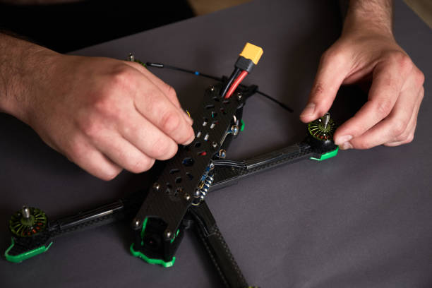 istock Close up of man's hands assembling a drone from parts, using tools, Preparing high-speed racing quadcopter for flight. Repair drone before training process. 1338600781