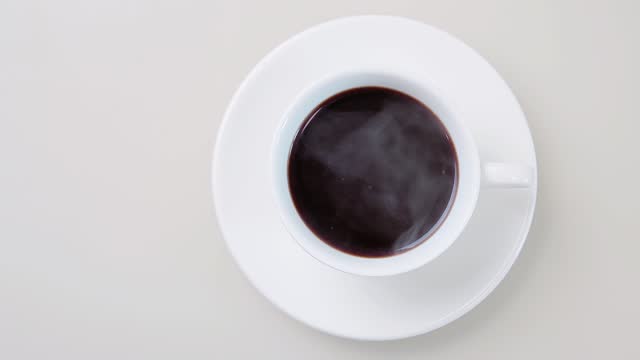 Cinemagraph, steaming fresh brewed hot coffee in a white cup, loop seamless motion, top view