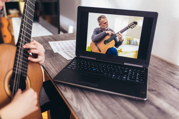 istock Girl playing guitar with computer, learn to play with an online course 1338601984