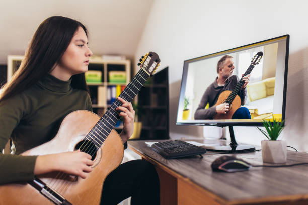 istock Girl playing guitar with computer, learn to play with an online course 1338602016