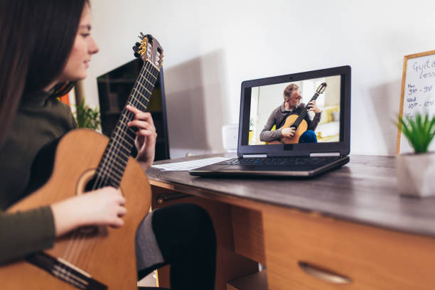 istock Girl playing guitar with computer, learn to play with an online course 1338602050