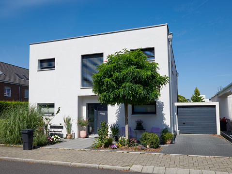 Cologne, Germany - August 25, 2021: Family house with garage and a front garden with a beautiful tree.