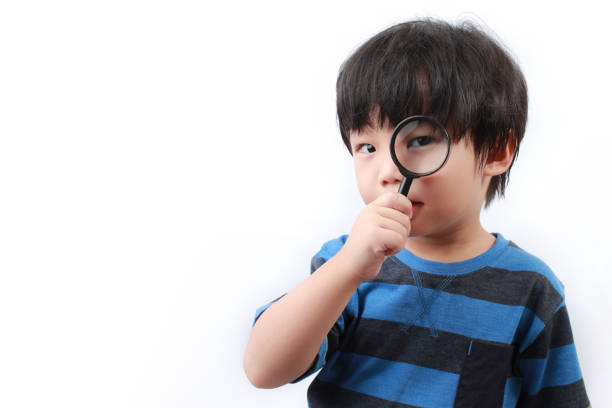 Boy looking through a magnifying glass stock photo