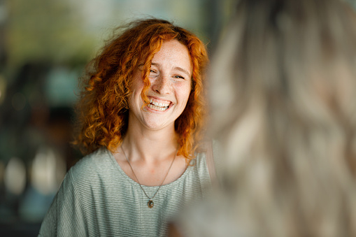 Cheerful redhead woman talking to her friend on the street.