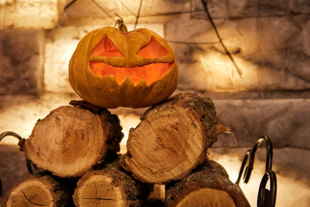 Glowing pumpkin for halloween night on firewood. Close-up, selective focus