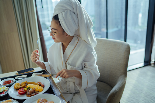 woman in a good mood to eat delicious food with the good atmosphere of the warm sunlight in the morning at the hotel room.