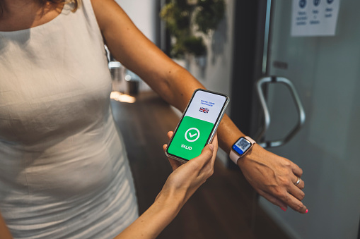 Vaccinated person using digital health passport on smart watch for travel during covid-19 pandemic. Scanning a QR code with a phone.