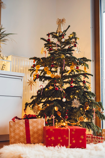 winter holidays, new year and celebration concept - gifts under decorated green artificial christmas tree at home