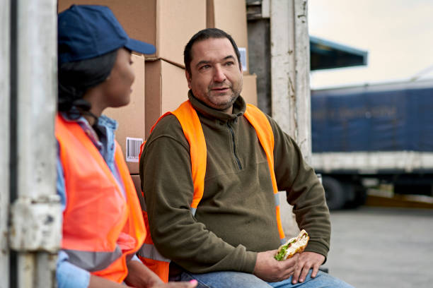 istock Trucker Eating Sandwich and Talking with Coworker 1338616191