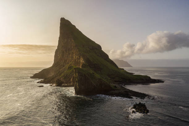Faroe Islands Tindholmur Rock Island Sunset Tindhólmur Vágar Island Faroe Islands Tindhólmur Rock Islet in the North Atlantic Ocean under atmospheric summer twlight cloudscape. Drone Point of view towards the harsh steep rock formation. Tindholmur Island close to Vágar Island on the southside of Sørvágsfjørður. Faroe Islands, Denmark, Nordic Countries, Europe vágar photos stock pictures, royalty-free photos & images