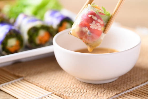 Vegan salad spring roll vegetable with edible flower dipping in sesame sauce