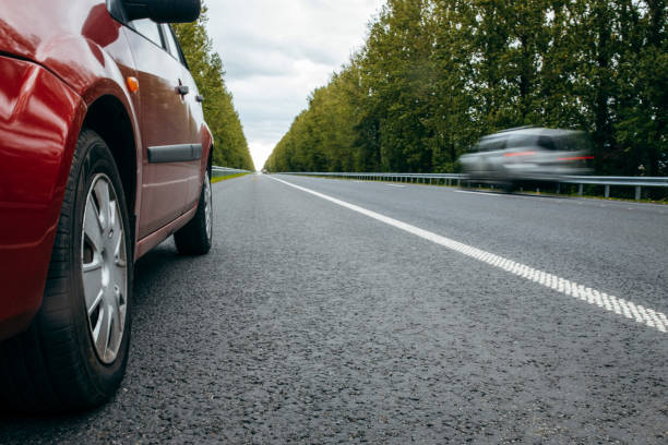 istock Car with low beam on, parked on road background nature green trees 1338624141