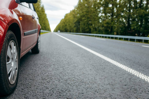 istock Car with low beam on, parked on road background nature green trees 1338624191