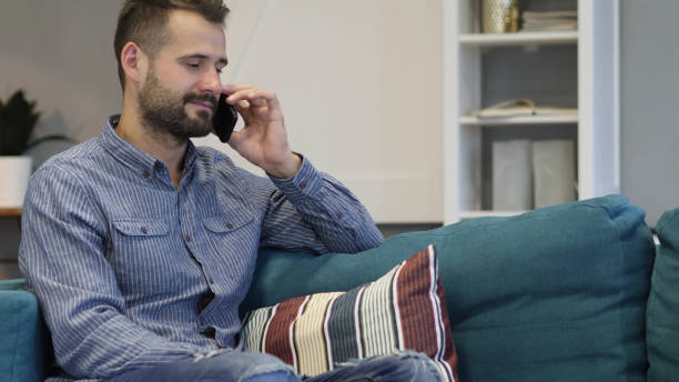 istock Man Talking on Phone, Sitting on Couch in Bedroom 1338626345