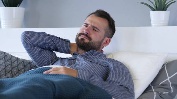 müder mann mit nackenschmerzen im bett - 16286 stock-fotos und bilder