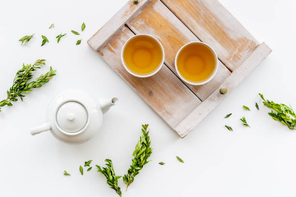 istock Black tea in cups with white teapot and green leaves 1338630482