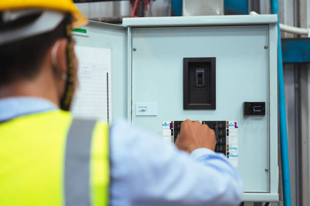 istock Engineer, Supervisor or Foreman male wear a mask, hard hat, and vest. Checking the power control box panel and electrical system inside the factory. for safety at work. 1338631409