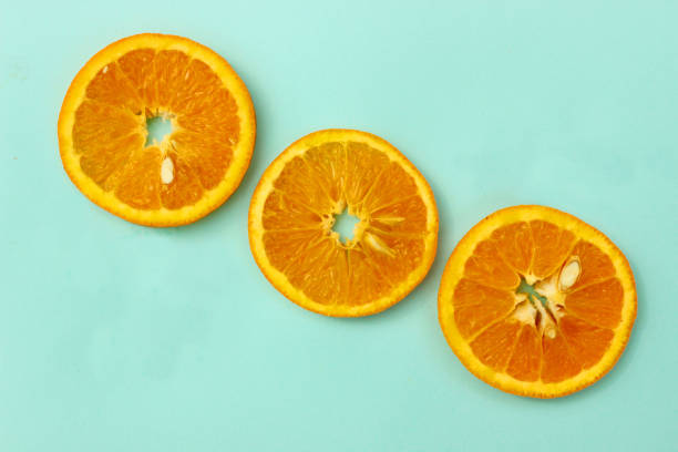 istock Image of three orange slices in diagonal row against pale blue-green background, elevated view 1338632780