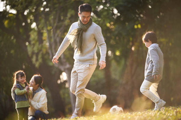 istock asian father playing soccer with son while mother and daughter watching 1338634082