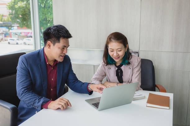 istock Two Asian business people working and discussing on new project at modern office 1338635924