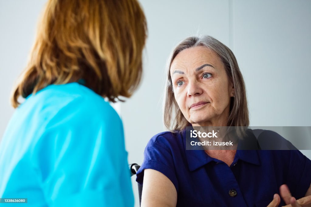 Depressed senior woman talking with nurse Worried elderly woman talking with nurse. Close up of face. Alzheimer's Disease Stock Photo