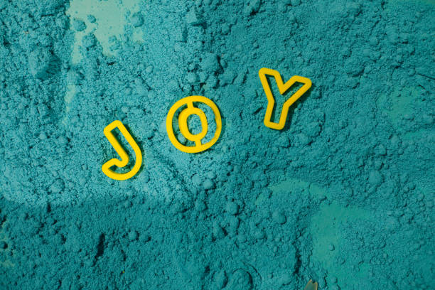 le mot joy, disposé sur du sable cinétique turquoise. la créativité des enfants. matériau pour la modélisation. hypoallergénique. détente. motricité fine . émotions joyeuses. thérapie par le sable - anticipation smiling touching image technique photos et images de collection